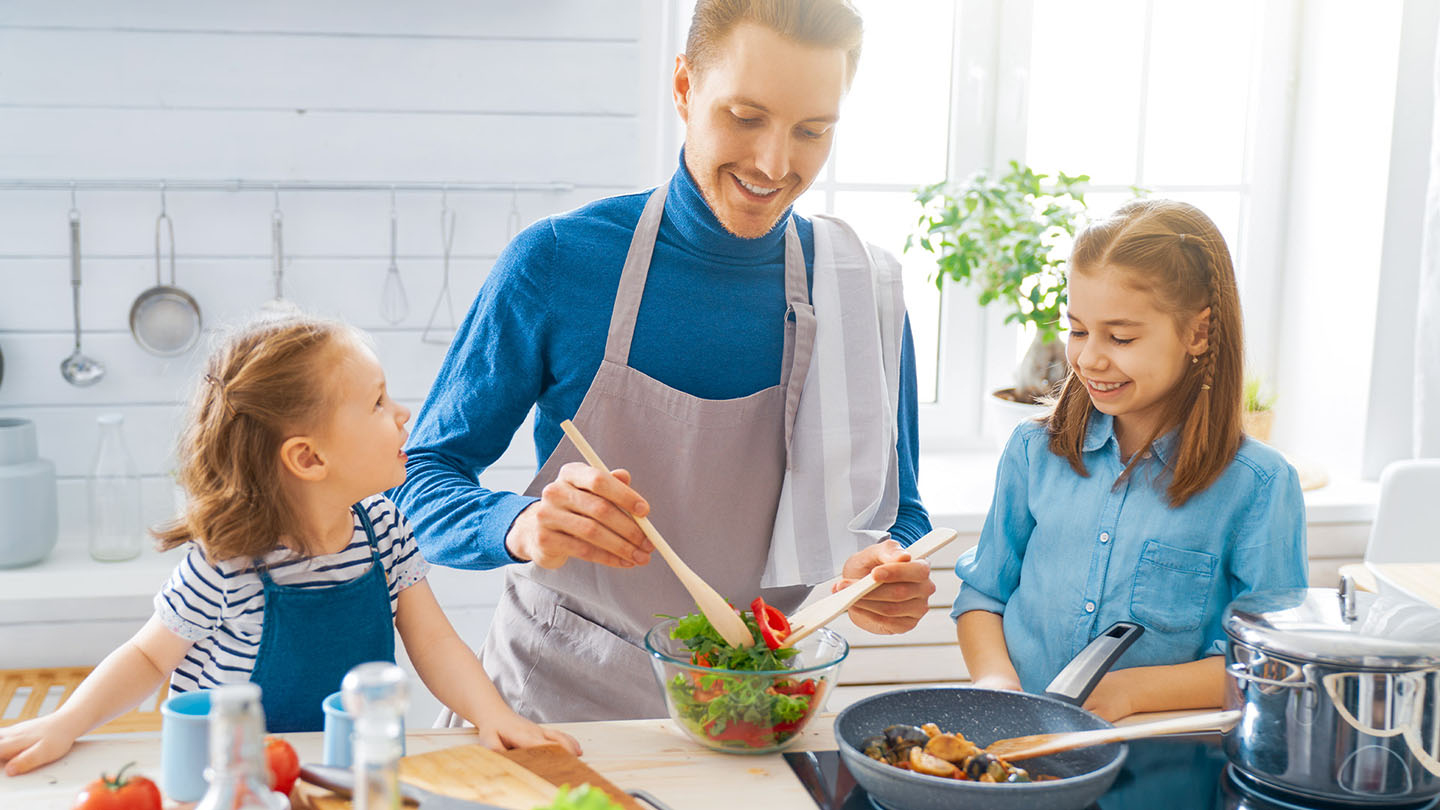 Семейство приготвя здравословна храна в кухнята.
