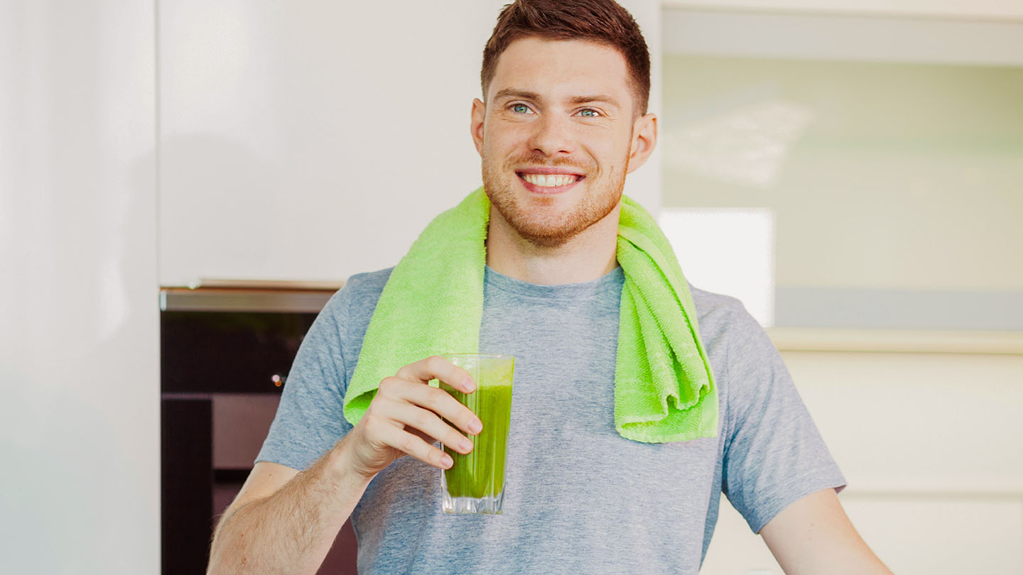 Мъж се наслаждава на здравословно зелено смути.
