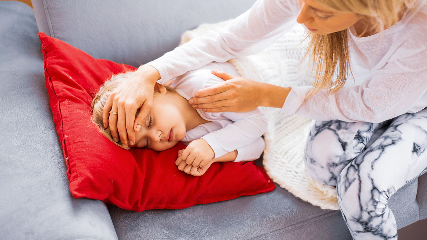 Майка мери температурата на болно дете.
