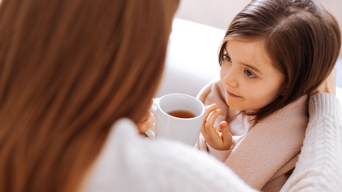 Майка предлага чай на дъщеря си, която е болна от грип.