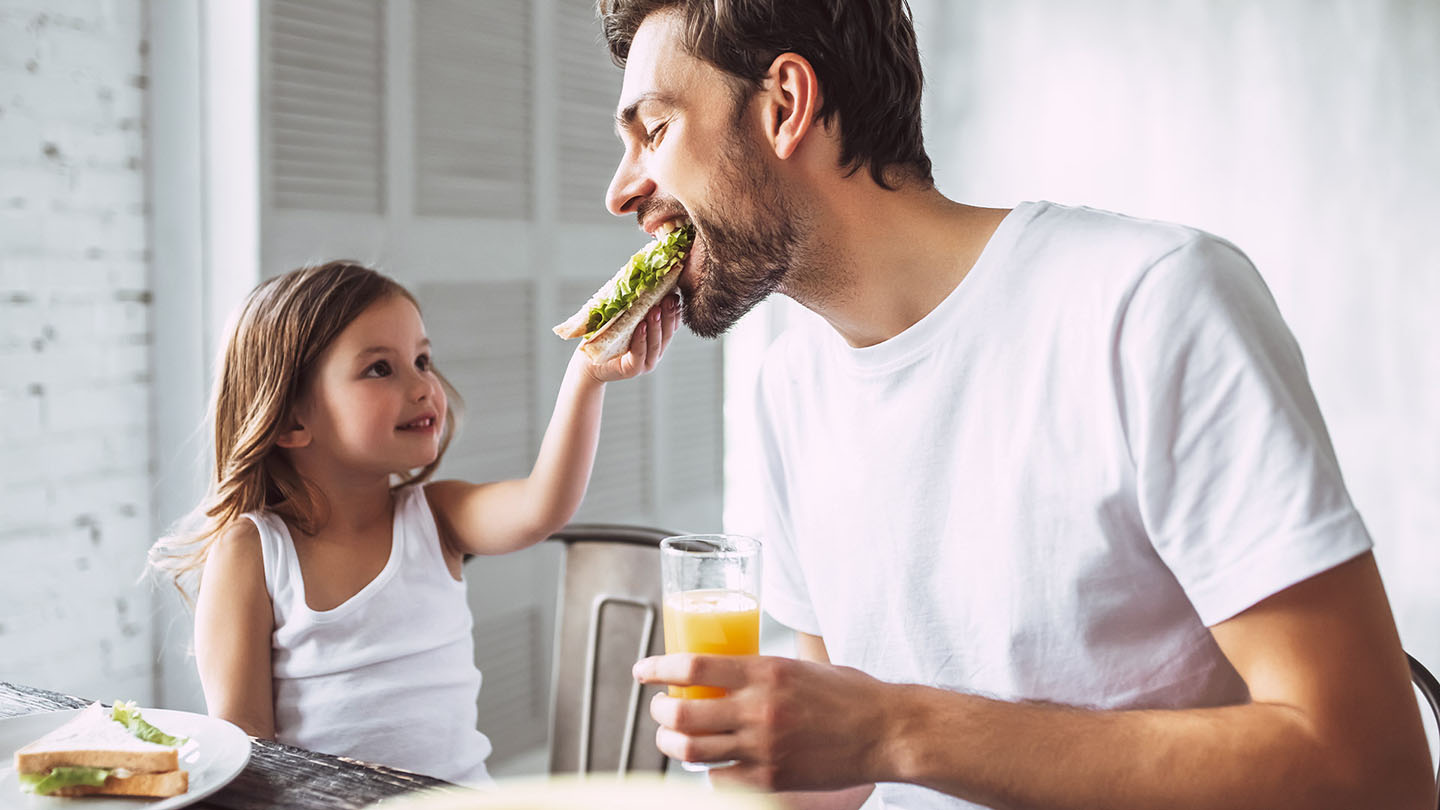 Баща и дете се наслаждават на сандвич.